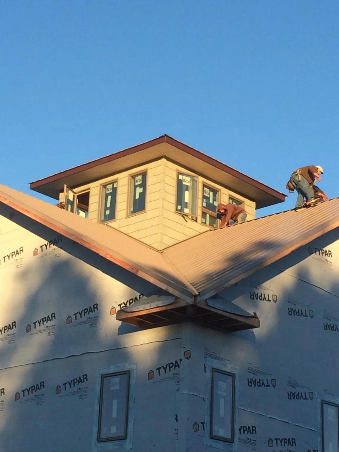 Roofers working around a rooftop cupola on a new metal roof at sunset — Roof Waterproofing in Benton by Roofing Brothers